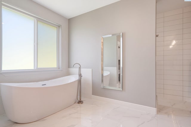full bathroom with baseboards, marble finish floor, and a freestanding tub