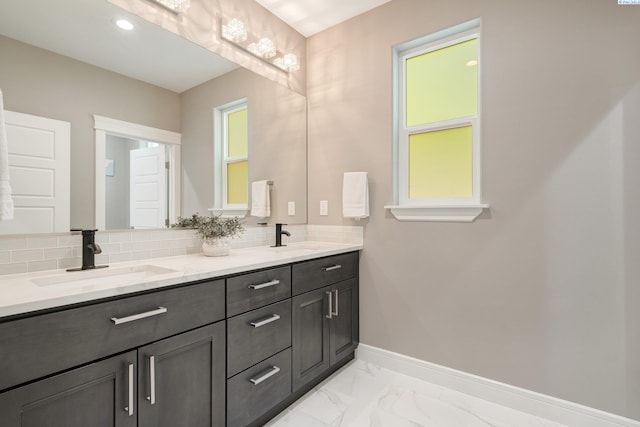 full bathroom with baseboards, marble finish floor, a sink, and decorative backsplash