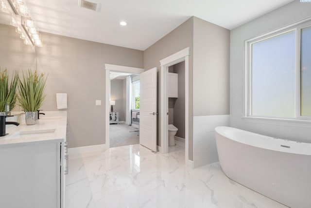 bathroom with visible vents, a freestanding bath, a sink, toilet, and recessed lighting