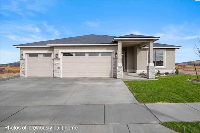 prairie-style house with stucco siding, a garage, driveway, a front lawn, and stone siding
