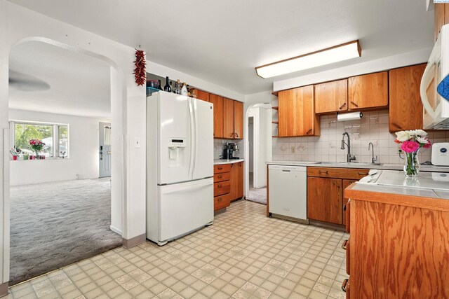 616 S Conway St, Kennewick, WA 99336 - kitchen featuring white appliances, a sink, arched walkways, and brown cabinetry