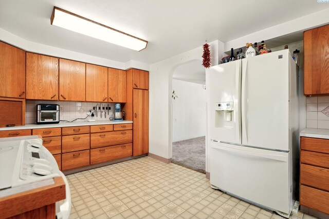 616 S Conway St, Kennewick, WA 99336 - kitchen with white fridge with ice dispenser, arched walkways, light countertops, and tasteful backsplash