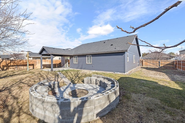 back of property featuring a patio, a shingled roof, an outdoor fire pit, a gate, and a fenced backyard