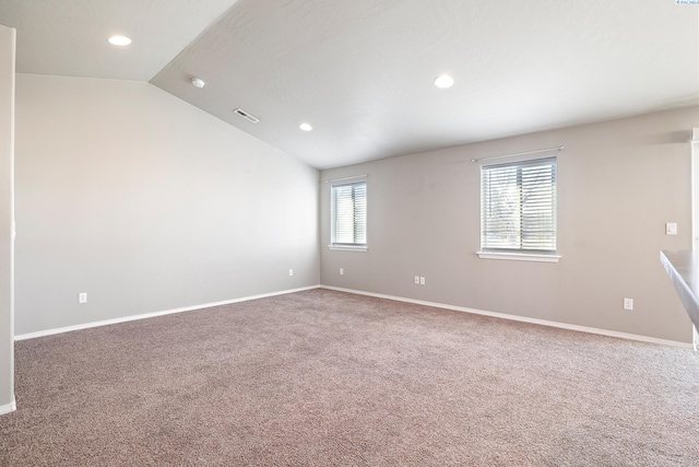 empty room with carpet floors, baseboards, visible vents, and vaulted ceiling