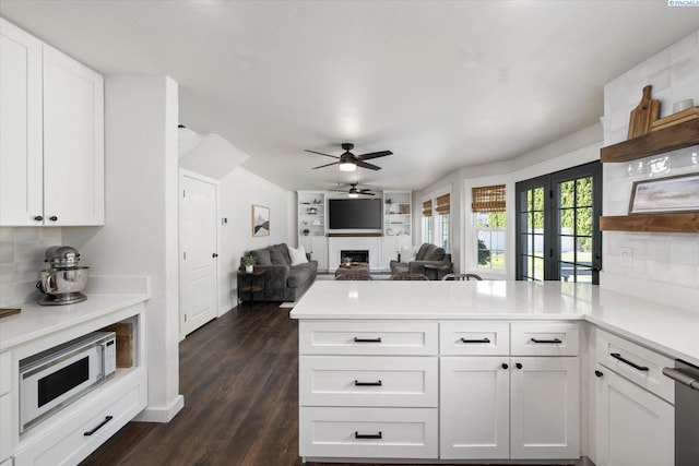 10219 W Argent Rd, Pasco, WA 99301 - kitchen featuring white microwave, a peninsula, a fireplace, ceiling fan, and white cabinets
