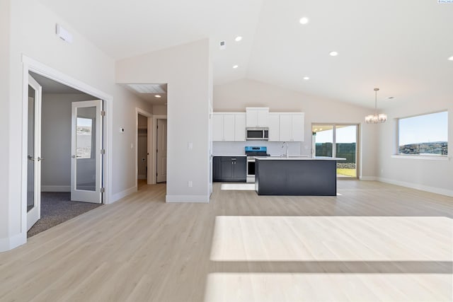 kitchen featuring stainless steel appliances, white cabinetry, open floor plan, light countertops, and decorative light fixtures