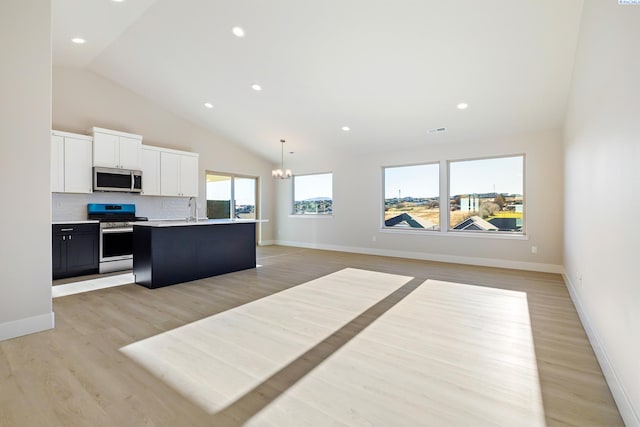 kitchen featuring a center island with sink, light countertops, appliances with stainless steel finishes, open floor plan, and white cabinetry