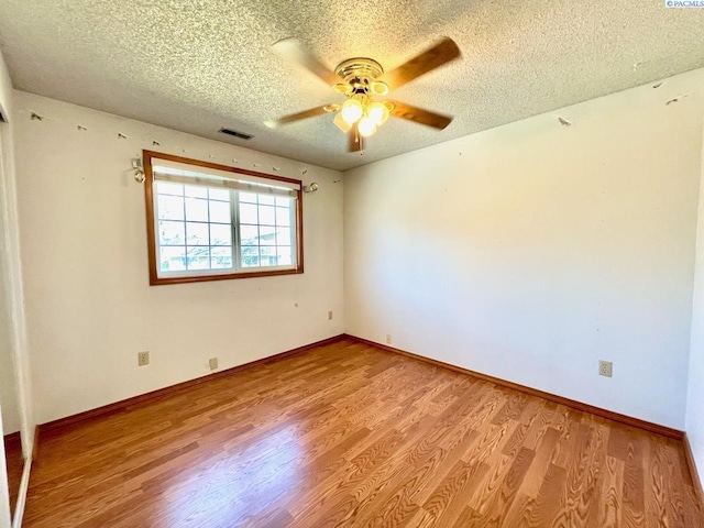 unfurnished room featuring a textured ceiling, light wood-style flooring, a ceiling fan, visible vents, and baseboards