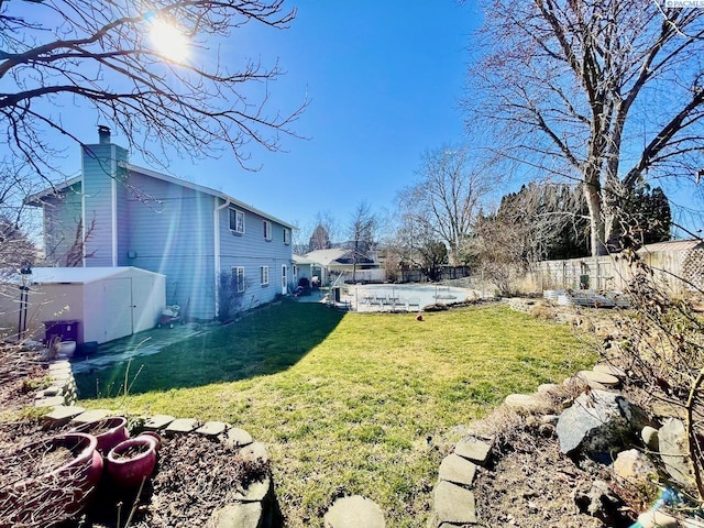 view of yard with a storage shed, a fenced backyard, and an outdoor structure