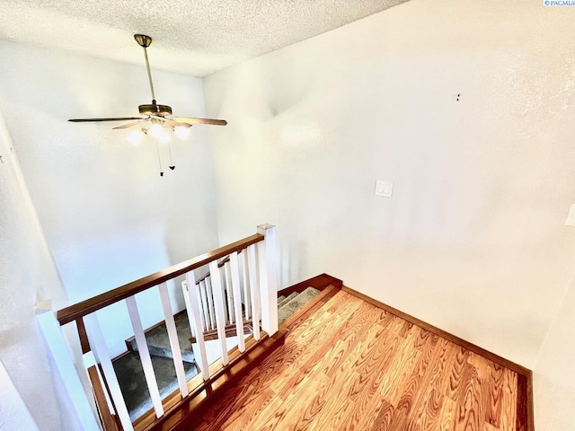 stairs with a textured ceiling and wood finished floors