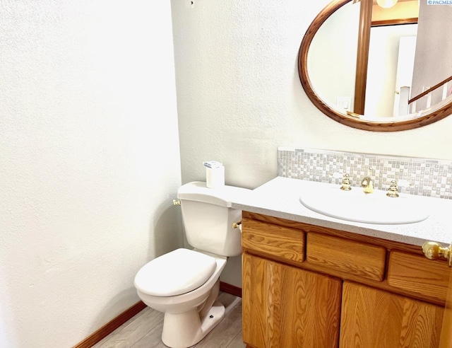 half bath with toilet, tasteful backsplash, and vanity