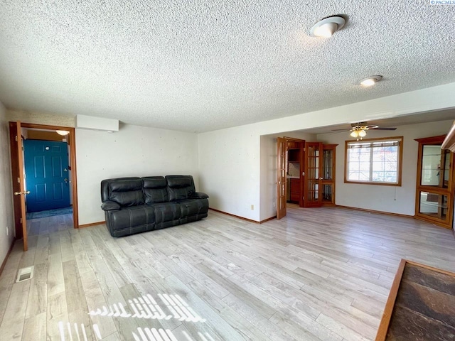 unfurnished living room featuring light wood-style flooring, a textured ceiling, visible vents, and baseboards