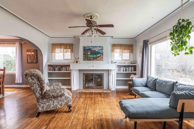 807 S Mill St, Colfax, WA 99111 - living area with arched walkways, a ceiling fan, wood finished floors, a fireplace, and baseboards