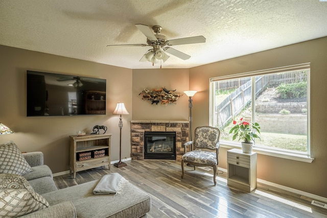 1135 SW Lost Trail Dr, Pullman, WA 99163 - living area featuring a textured ceiling, a ceiling fan, wood finished floors, and a stone fireplace