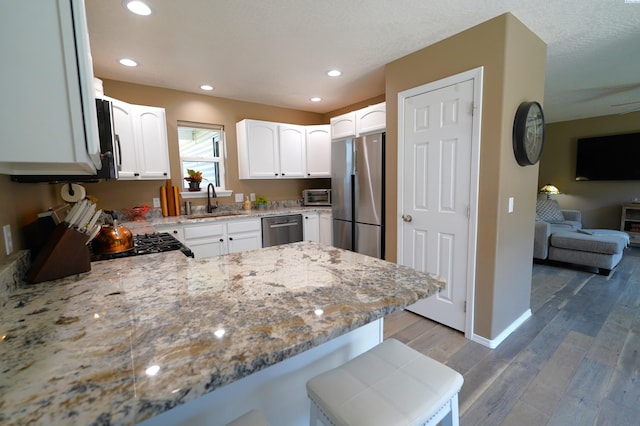 1135 SW Lost Trail Dr, Pullman, WA 99163 - kitchen with appliances with stainless steel finishes, light stone counters, light wood-style flooring, white cabinetry, and open floor plan