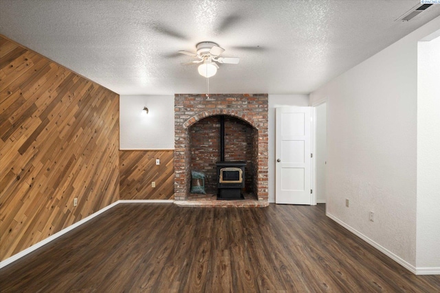 2714 W John Day Ave, Kennewick, WA 99336 - unfurnished living room with a wood stove, wooden walls, ceiling fan, baseboards, and wood finished floors