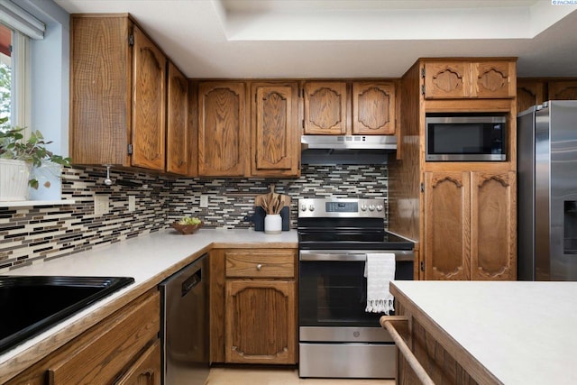 2714 W John Day Ave, Kennewick, WA 99336 - kitchen featuring stainless steel appliances, a raised ceiling, brown cabinets, light countertops, and tasteful backsplash