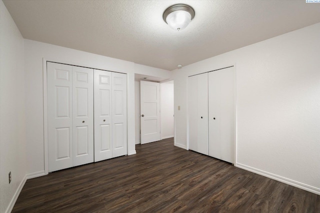 2714 W John Day Ave, Kennewick, WA 99336 - unfurnished bedroom with dark wood-type flooring, two closets, baseboards, and a textured ceiling