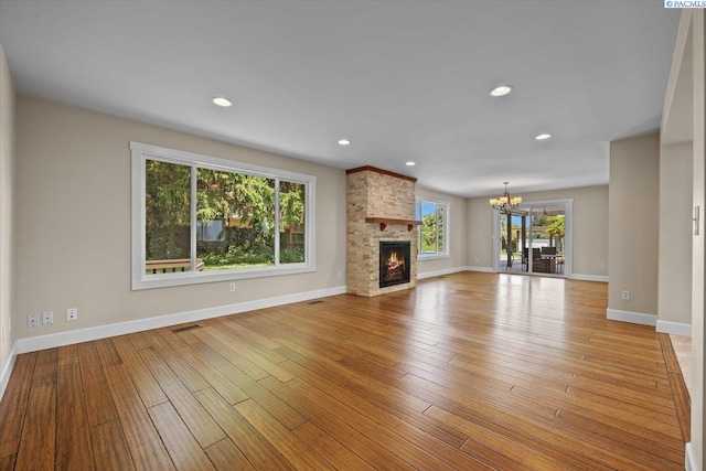 707 N Quillan St, Kennewick, WA 99336 - unfurnished living room featuring a chandelier, light wood finished floors, a stone fireplace, and recessed lighting