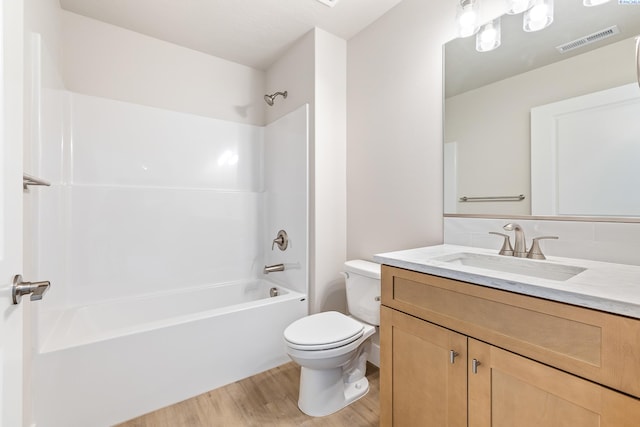 bathroom featuring wood finished floors, toilet,  shower combination, and vanity