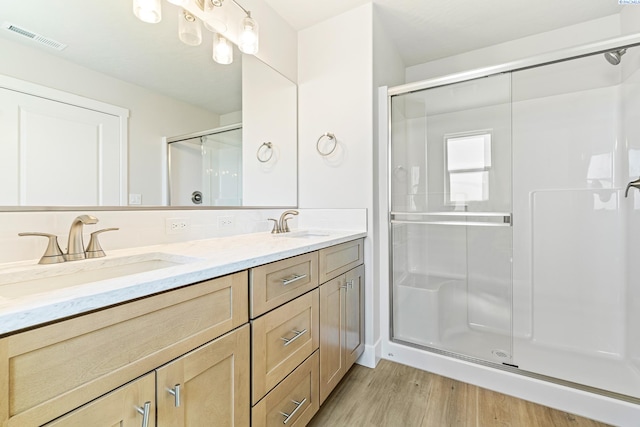 full bath with a shower stall, wood finished floors, and double vanity