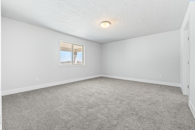 spare room featuring carpet, a textured ceiling, and baseboards