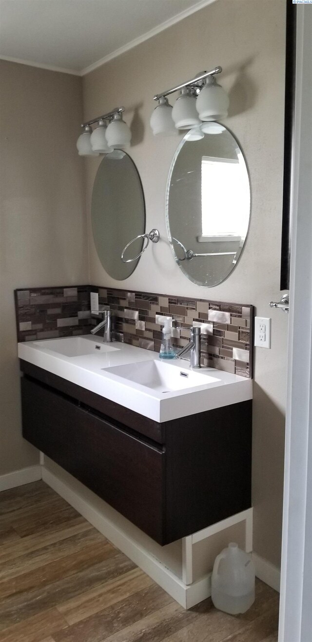 1529 Mcpherson Ave, Richland, WA 99352 - bathroom featuring crown molding, wood finished floors, baseboards, decorative backsplash, and double vanity
