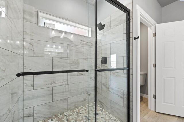 full bath with toilet, a shower stall, and wood finished floors
