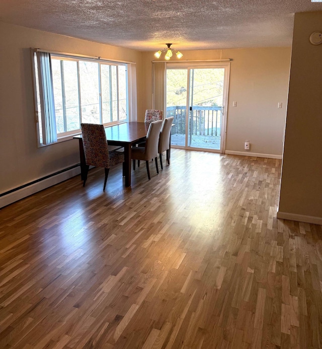 unfurnished dining area featuring dark wood-type flooring, a textured ceiling, and a baseboard heating unit