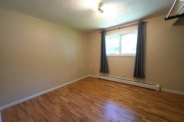 unfurnished room featuring a baseboard radiator, wood-type flooring, and a textured ceiling