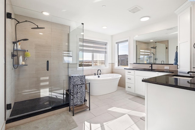 bathroom featuring a stall shower, visible vents, a soaking tub, vanity, and tile walls