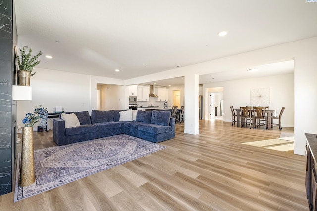 living room featuring light wood-type flooring, baseboards, and recessed lighting