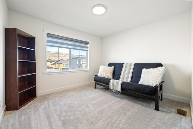 living area with visible vents, baseboards, and light colored carpet