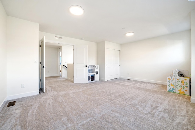 spare room featuring baseboards, visible vents, and light colored carpet