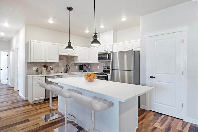 kitchen featuring pendant lighting, sink, stainless steel appliances, white cabinets, and dark hardwood / wood-style flooring