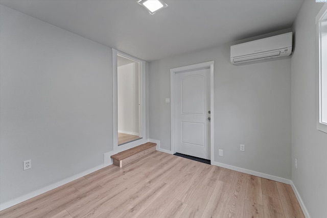 empty room with a wall mounted air conditioner, baseboards, and wood finished floors