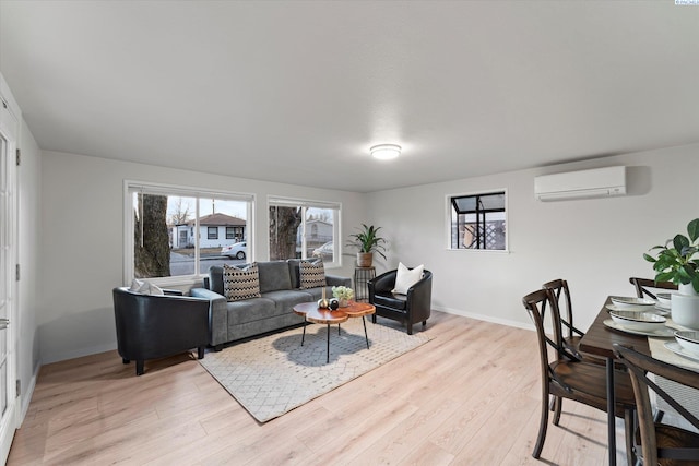 living area with a wall unit AC, light wood-style flooring, and baseboards