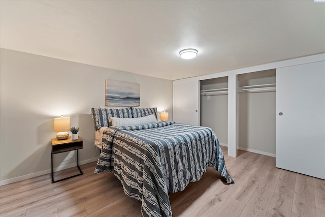 bedroom featuring light wood-type flooring, baseboards, and two closets