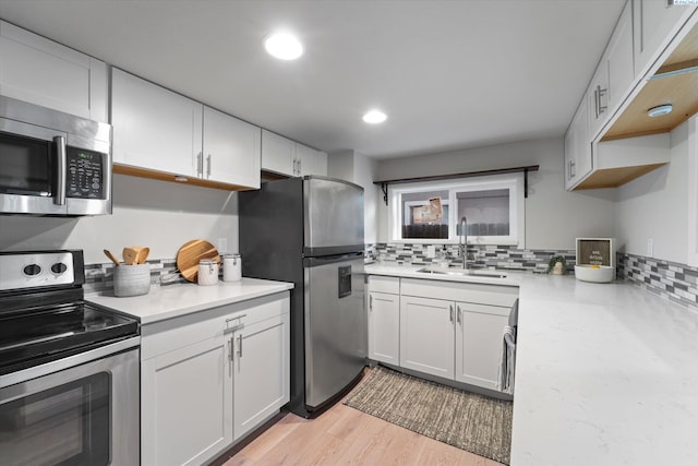 kitchen featuring recessed lighting, a sink, appliances with stainless steel finishes, backsplash, and light wood finished floors