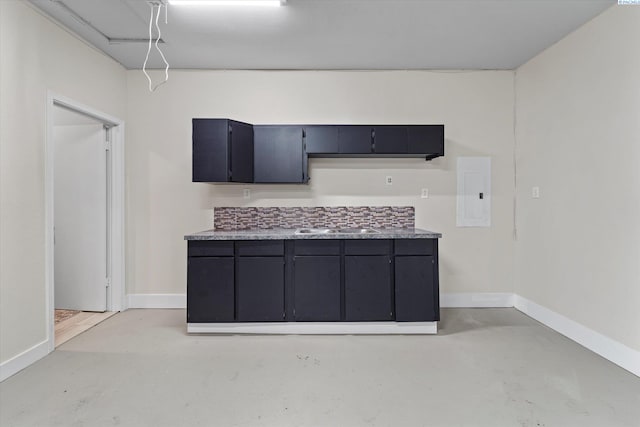 kitchen with a sink, electric panel, baseboards, and concrete flooring