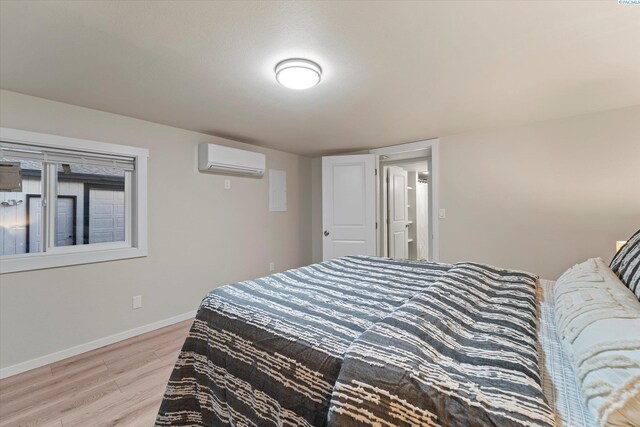 bedroom with baseboards, wood finished floors, and a wall mounted air conditioner