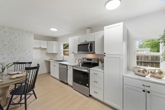 732 W Henry St, Pasco, WA 99301 - kitchen featuring stainless steel appliances, light wood finished floors, light countertops, white cabinetry, and decorative backsplash
