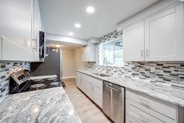 340-342 NW N St, Pullman, WA 99163 - kitchen featuring tasteful backsplash, appliances with stainless steel finishes, a sink, white cabinetry, and light wood-type flooring