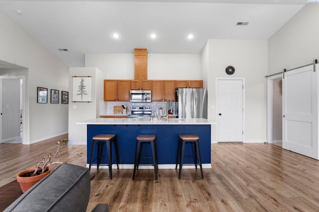 1707 W 25th Pl, Kennewick, WA 99337 - kitchen featuring appliances with stainless steel finishes, a barn door, brown cabinetry, light countertops, and backsplash