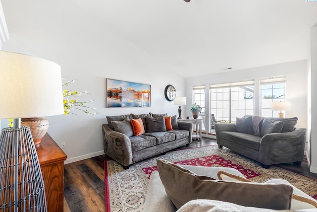 living area featuring lofted ceiling, visible vents, baseboards, and wood finished floors