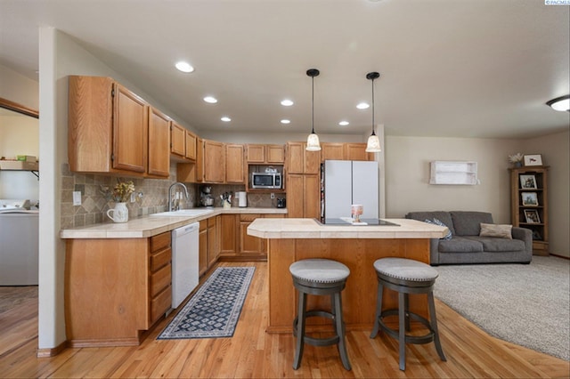 2302 W 31st Ave, Kennewick, WA 99337 - kitchen featuring white appliances, washer / dryer, tile counters, a center island, and light wood-style flooring