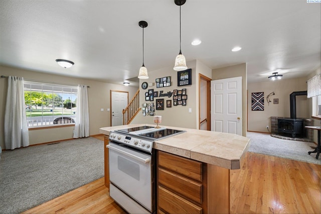2302 W 31st Ave, Kennewick, WA 99337 - kitchen with white range with electric cooktop, open floor plan, a wood stove, light wood-style flooring, and pendant lighting