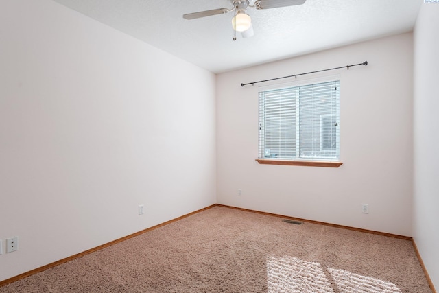 unfurnished room with carpet floors, visible vents, ceiling fan, and baseboards