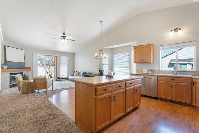 kitchen featuring light countertops, open floor plan, a sink, a tile fireplace, and dishwasher