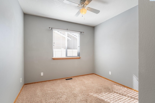 carpeted spare room featuring visible vents, ceiling fan, and baseboards